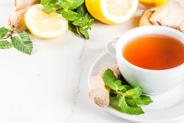 Taza de té de jengibre con limón, menta fresca y miel, sobre marba blanca
 - Foto, imagen