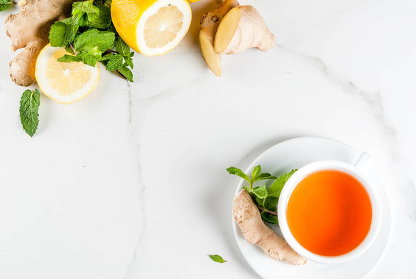 Cup of ginger tea with lemon,fresh mint and honey, on white marb - Photo, Image