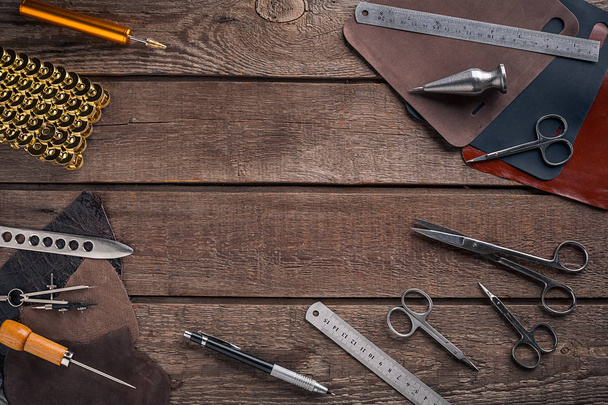 Leather craft or leather working. Leather working tools and cut out pieces of leather on work desk . - Photo, Image