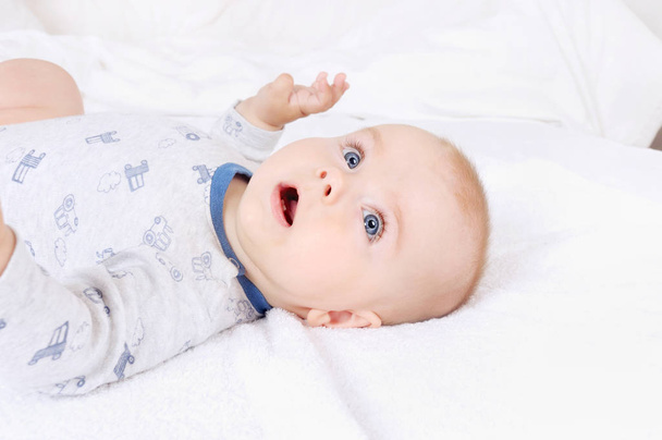ベッドに横になっている青い目の面白い赤ちゃん幼児子供 - 写真・画像
