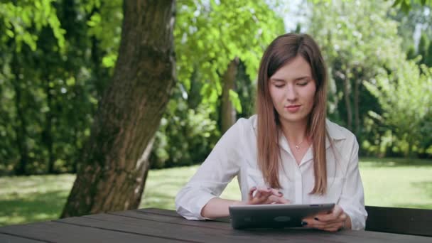 Jovencita usando un iPad en el parque
 - Imágenes, Vídeo