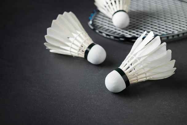 Shuttlecocks and badminton racket on black background. - Фото, изображение
