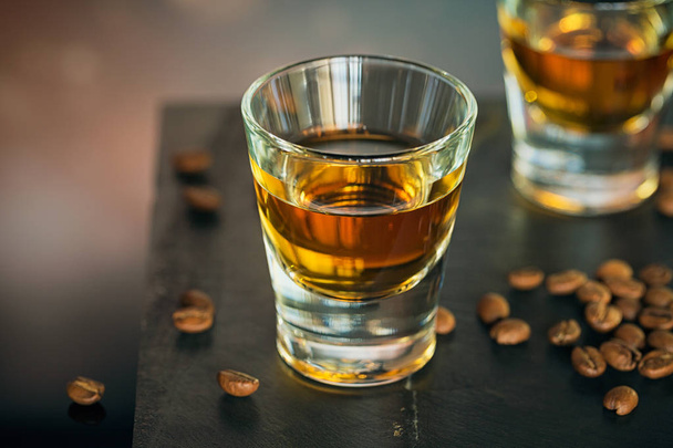Cognac or liqueur, coffee beans and spices on a glass table. - Фото, изображение