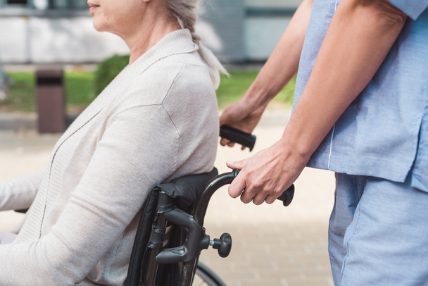 sairaanhoitaja ja vanhempi nainen pyörätuolissa
 - Valokuva, kuva