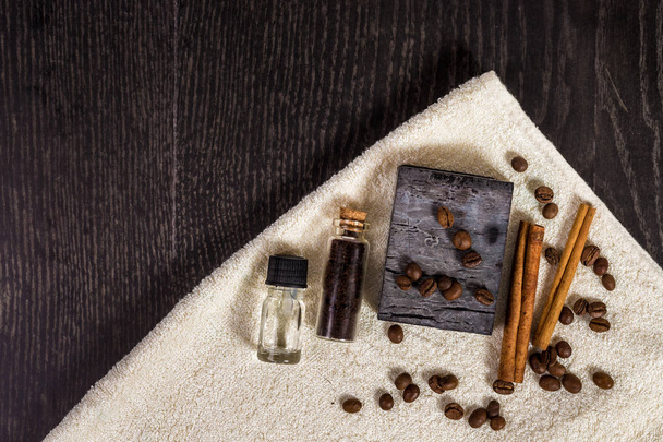 ブラウンのスパ: 天然石けん、アロマオイル、シナモンスティック、コーヒー豆、ウッドの背景にタオル. - 写真・画像