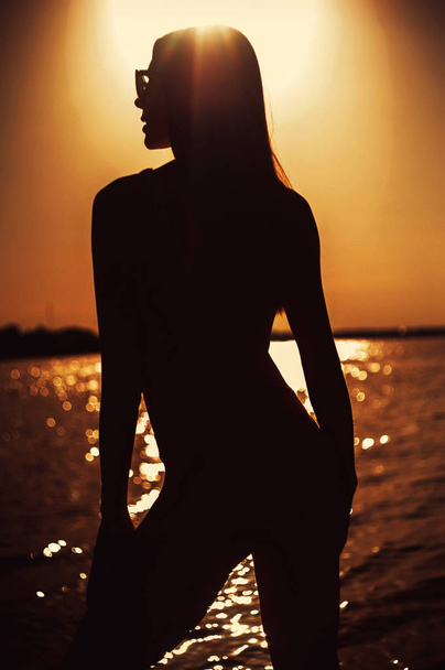 Mooie jonge vrouw ta zonsondergang - Foto, afbeelding