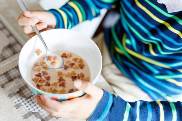 Primer plano de las manos del niño comiendo cereales caseros para el desayuno o el almuerzo
 - Foto, imagen