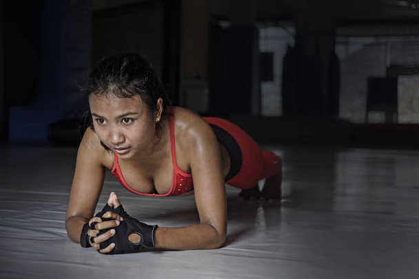 Sexy spocony Asian kobieta w odzież sportową, leżącego na pozycji deski na podłodze sali gimnastycznej dojo w ciężkich treningów fitness trening - Zdjęcie, obraz