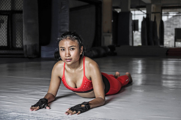 jovem bonito suado asiático mulher no esporte roupas esticando no gymm dojo chão sorrindo posando corporativa
 - Foto, Imagem