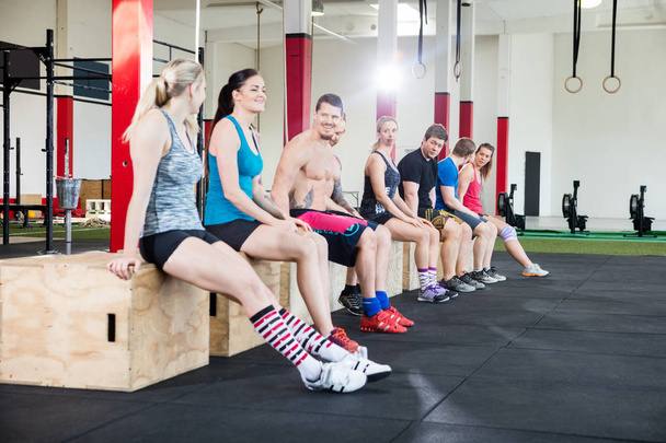Atletas sentados em caixas durante a pausa de treino no ginásio
 - Foto, Imagem