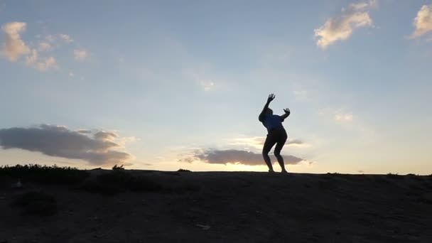 Boldog fiatalember magasra ugrik, és taps a kezét, egy hegyvidéki területen, napnyugtakor a Slo-Mo - Felvétel, videó