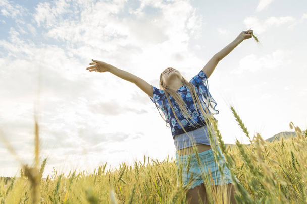 Чарівна маленька дівчинка грає в пшеничному полі в теплий літній день
 - Фото, зображення