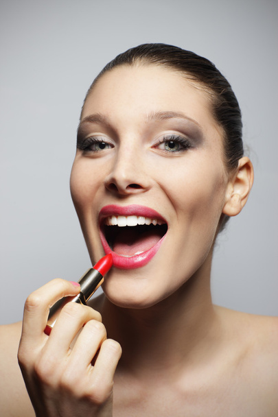 Woman applying red lipstick - 写真・画像