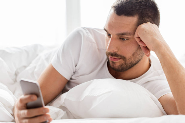 close up of man with smartphone in bed in morning - Φωτογραφία, εικόνα
