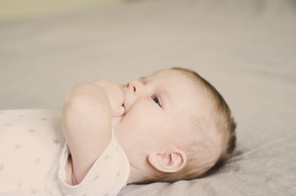 close up picture of beautiful little baby with hand in mouth - Photo, Image