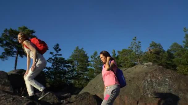 Két aktív fiatal nők segíthetnek egymásnak mászni a magas szikla - Felvétel, videó
