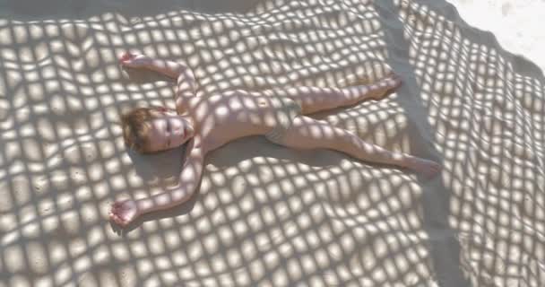 Дитина робить ангела піску, коли відпочиває на пляжі
 - Кадри, відео