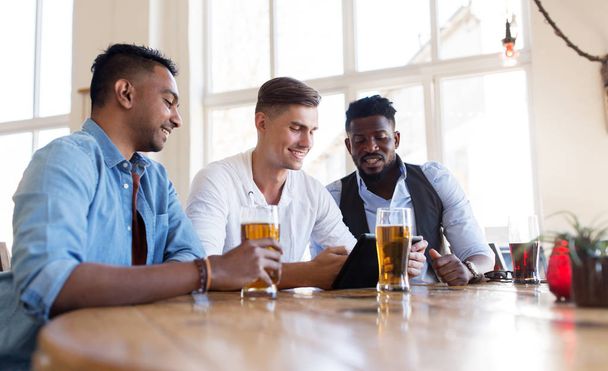male friends with tablet pc drinking beer at bar - Photo, image