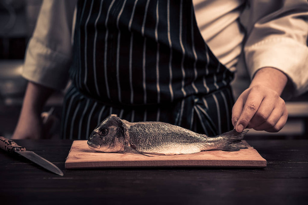 Chef cortando el pescado en una tabla
 - Foto, Imagen