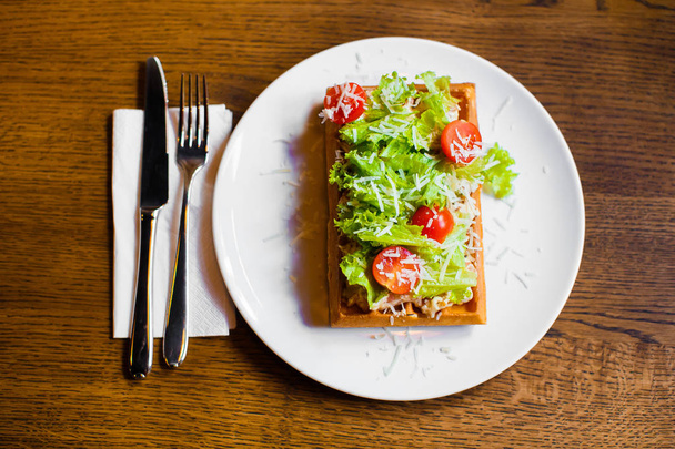 The above composition of the food. The belgian waffles with vegetables such as tomatoes, salat and cheese. - Φωτογραφία, εικόνα