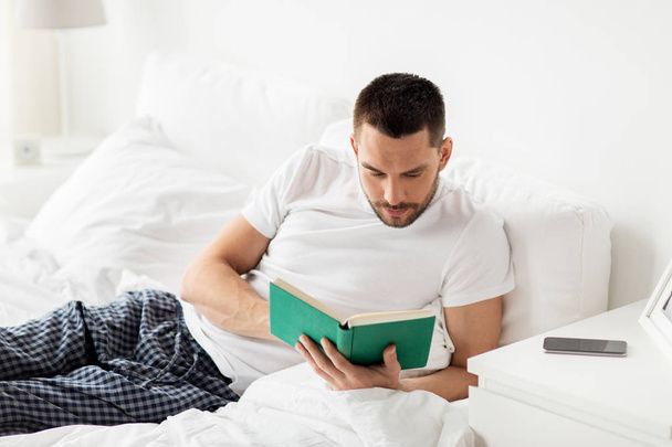 man reading book in bed at home - Zdjęcie, obraz