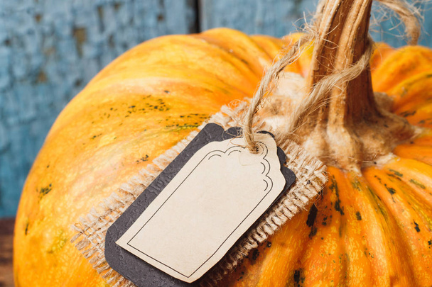Orange pumpkin with decorative tag, wooden background - Photo, Image