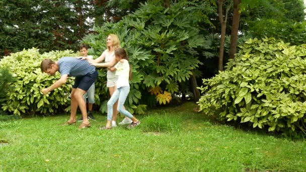 Onnellinen perhe tanssii yhdessä nurmikolla puistossa kauniin luonnon kanssa. Neljä tonnia. Kopioi elämäntapa
 - Materiaali, video