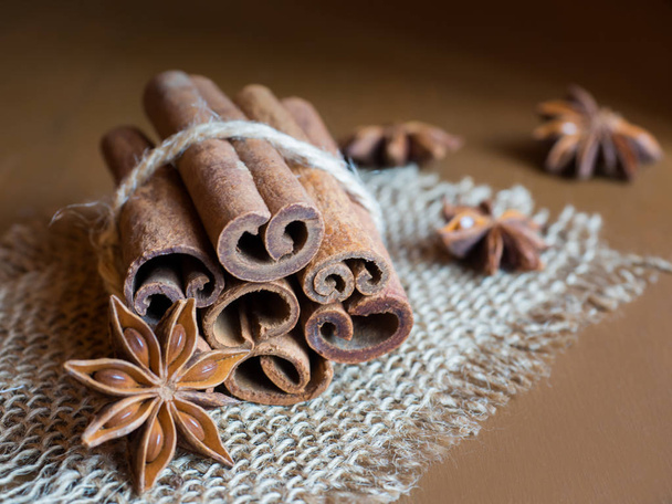 Kaneelstokjes gekoppeld door een tekenreeks op jute bruin houten achtergrond - Foto, afbeelding