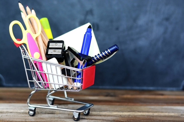 Back to school concept - shopping cart with school supplies over chalkboard - Photo, Image