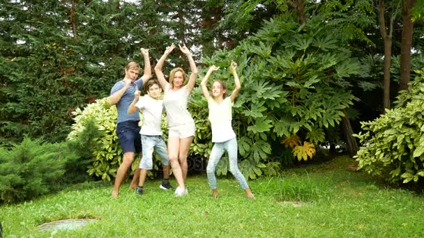 glückliche Familie, die zusammen auf dem Rasen in einem Park mit schöner Natur tanzt. 4k. Kopierraum. Lebensstil - Filmmaterial, Video