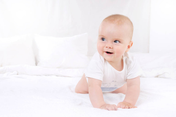 Adorable baby boy in white sunny bedroom - Fotó, kép