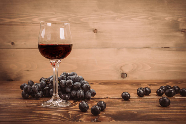 Glass of red wine and grapes on rustic wood table - Fotoğraf, Görsel