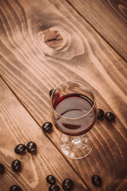Glass of red wine and grapes on rustic wood table - Foto, imagen