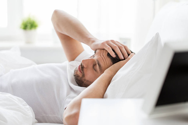 мужчина в постели дома страдает от головной боли
 - Фото, изображение