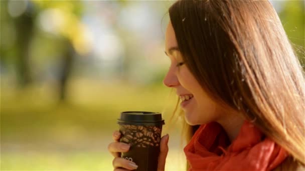 Autumn Girl Drinking Coffee. Fall Concept of Young Woman Enjoying Hot Drink from Disposable Coffee Cup in Fall Park - Materiał filmowy, wideo