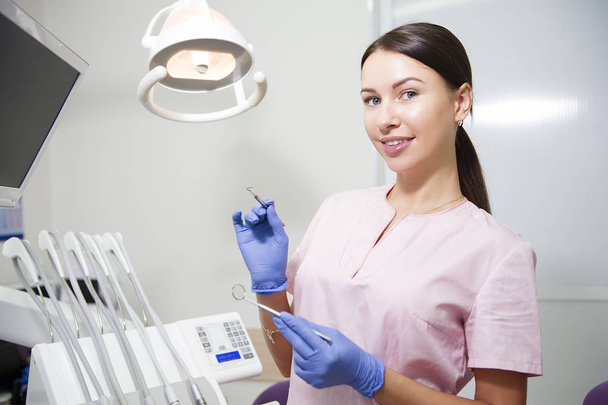 Happy young female dentist over medical office background - Foto, afbeelding