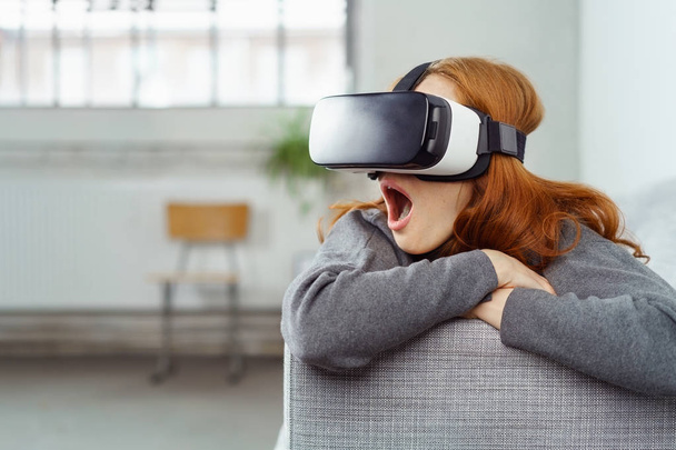 Astonished young woman using a VR headset - Fotó, kép
