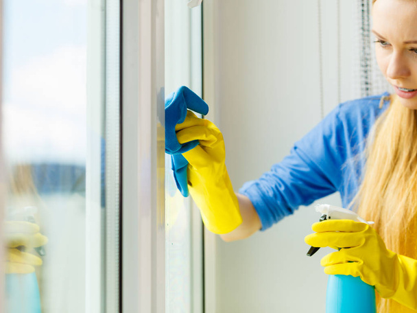 Girl cleaning window at home using detergent rag - Fotó, kép