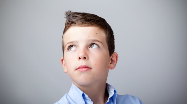 Close up portrait of boy looking up on grey background - Фото, зображення