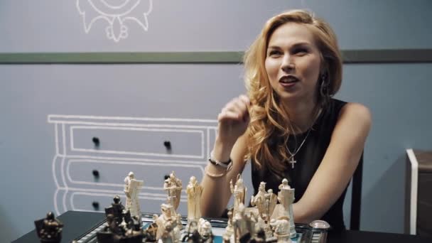 Krásná mladá blondýnka hraje šachy s mužem v brýlích a začne smát - Záběry, video