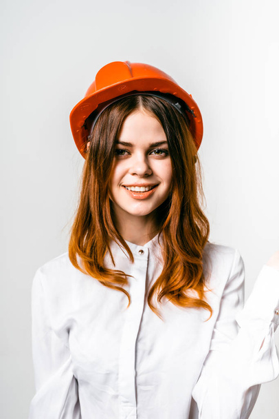 Young woman in a construction worker's helmet on a white background - Фото, изображение