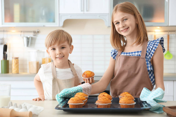 Boy and girl with muffins in kitchen. Cooking classes concept - Фото, зображення