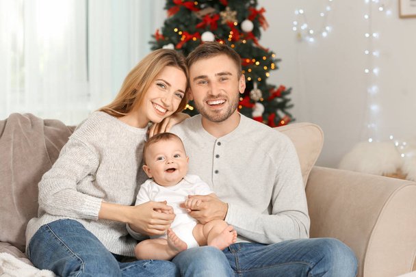 Happy parents with baby in decorated room for Christmas - Foto, afbeelding