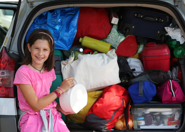 niña carga las bolsas en el maletero de su coche
 - Foto, Imagen