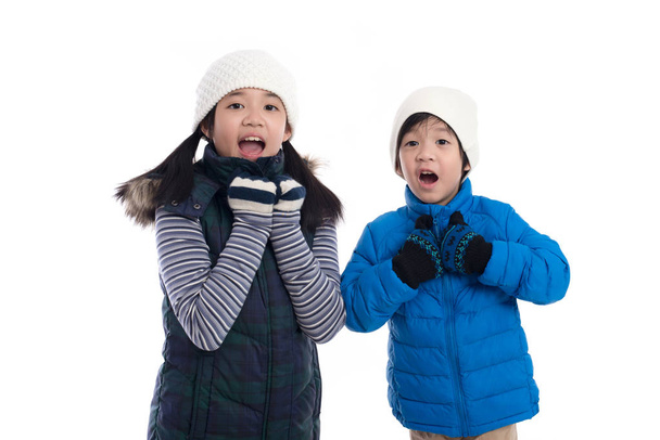 Söpö Aasian lapset talvivaatteissa on yllätys ja niin onnellinen siitä valkoisella taustalla eristetty.
 - Valokuva, kuva