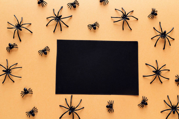 Black blank paper card with decorative spiders on orange backgro - Фото, изображение