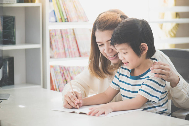 asiatische Mutter hilft ihrem Sohn Hausaufgaben auf weißem Tisch - Foto, Bild