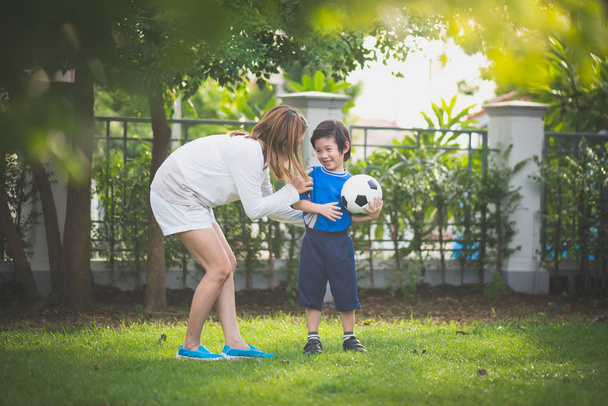 Asiatique mère et fils jouer au football dans le parc ensemble
 - Photo, image