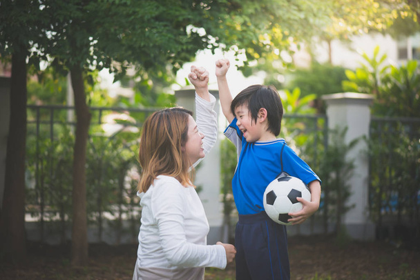 Asiática madre e hijo jugando fútbol en parque juntos
 - Foto, imagen