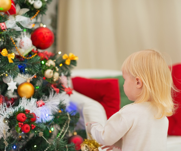 Baby decorating Christmas tree. Rear view - Foto, Imagen
